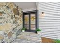 Elegant double doors framed by stone and siding with potted plants and wreaths at 2435 Roxburgh Dr, Roswell, GA 30076