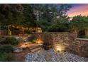 Beautifully landscaped backyard featuring stone steps and walls, illuminated by outdoor lighting at 979 Pathview Ct, Dacula, GA 30019