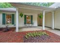 Inviting front porch featuring hanging ferns, a small table with chairs and decorative landscaping at 3318 Freedom Lndg, Kennesaw, GA 30144