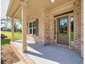 Charming covered front porch featuring brick columns and a stylish front door with sidelights at 741 Cams Crk, Mcdonough, GA 30253