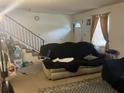 Living room featuring stairs, front door, couch with cover, and window with curtain at 6354 Shannon Pkwy # 26C, Union City, GA 30291