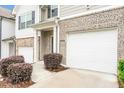View of a townhome featuring a one-car garage and manicured landscaping for a welcoming entrance at 5668 Union Pointe Dr, Union City, GA 30291