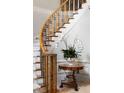 Close up of curved staircase with white and grey carpet, iron railings, and a side table with floral arrangement at 3639 Paper Mill Se Rd, Marietta, GA 30067