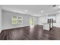 Bright, open-concept living space with dark wood floors, an island kitchen, and sliding glass doors at 1998 Nuthatch Dr, Hoschton, GA 30548