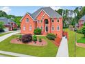 Charming two-story brick home boasts a lush lawn, mature trees, and inviting curb appeal at 240 Flowers Cove Ln, Lilburn, GA 30047