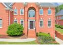 Elegant brick home featuring a stately entrance with a beautiful front door and manicured landscaping at 240 Flowers Cove Ln, Lilburn, GA 30047