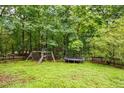 Large backyard featuring a playset and trampoline surrounded by trees at 305 Saddle Wood Dr, Canton, GA 30114