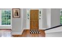 A welcoming entryway with hardwood floors, sidelight windows, a wooden door, and a decorative black and white mat at 1625 Clark Lake Nw Dr, Acworth, GA 30102