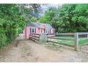 Side view of charming pink house with fenced yard, driveway and a detached garage in a wooded setting at 207 Walthall Nw St, Marietta, GA 30064