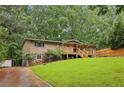 Charming home featuring a well-manicured lawn, stone accents, a welcoming front porch, and surrounded by mature trees at 3115 Chimney Cove Ln, Cumming, GA 30041
