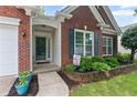 Inviting entrance with brick facade, colorful plants, and dark green shutters at 6360 Waveland Dr, Cumming, GA 30040