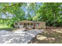Single story home with front porch, long concrete driveway, mature trees, and green lawn at 2017 S Deshon Rd, Lithonia, GA 30058