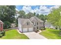 View of brick two-story home with mature trees, manicured lawn, and two-car garage at 445 Sweet Ivy Ln, Lawrenceville, GA 30043