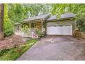 Charming home featuring a welcoming front porch, a two-car garage, and colorful landscaping at 1526 Oakleaf Dr, Auburn, GA 30011