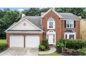 Close-up of a brick two-story home with a two-car garage, front yard landscaping, and arched window feature at 3614 Clearbrooke Way, Duluth, GA 30097