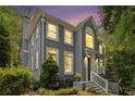 Beautiful gray painted brick home with white trim surrounded by mature trees and manicured landscaping at dusk at 29 Greenland Trce, Atlanta, GA 30342