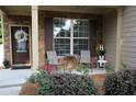 Inviting covered front porch with brick, seating, and a decorative wreath on the front door at 5230 Centennial Hill Nw Dr, Acworth, GA 30102