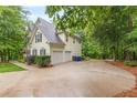 Side view of home, driveway, and attached garage, all enhanced by lush landscaping and natural surroundings at 5767 Wembley Dr, Douglasville, GA 30135