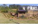 Welcoming community entrance sign with brick accents, manicured landscaping, and a black iron fence at 12086 Conrad Cir, Hampton, GA 30228