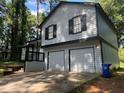 Two-story home with a two-car garage, black trim, and mature trees surrounding the property at 4064 Panola Woods Dr, Stonecrest, GA 30038