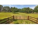 Fenced-in backyard with a large grassy area and mature trees providing shade and privacy at 100 Marshas Vineyard, Hampton, GA 30228