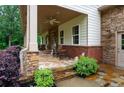 Inviting front porch with stone flooring, ceiling fan, and comfortable seating area at 7131 Ridge Rd, Hiram, GA 30141