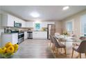 Bright kitchen and dining area featuring white cabinets, stainless steel appliances, and modern flooring at 4457 Lincoln Jones Rd, Ellenwood, GA 30294