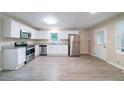 Well-lit kitchen with modern stainless steel appliances, clean white cabinets and sleek gray laminate flooring at 4457 Lincoln Jones Rd, Ellenwood, GA 30294