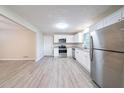 Spacious kitchen featuring stainless steel appliances, white cabinetry, and modern laminate flooring at 4457 Lincoln Jones Rd, Ellenwood, GA 30294