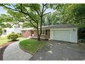 Brick home showcasing a well-maintained lawn, mature trees, and a convenient driveway at 2394 Burch Ne Cir, Brookhaven, GA 30319