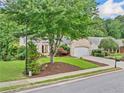 Lovely front exterior featuring manicured lawn, landscaping, and a brick facade at 554 Grand Ashbury Ln, Sugar Hill, GA 30518