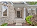A close-up view of the front porch with brick steps, white pillars, and a dark front door at 554 Grand Ashbury Ln, Sugar Hill, GA 30518
