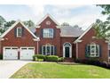 Beautiful red brick home with black shutters, a two-car garage and a well-maintained lawn at 4046 Creekview Ridge Dr, Buford, GA 30518
