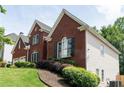 Two-story red brick home with well-manicured landscaping with shrubs and green grass lawn at 4046 Creekview Ridge Dr, Buford, GA 30518