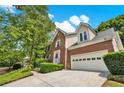A beautifully landscaped two story home with brick and siding, mature trees, and an attached garage at 230 Channings Lake Dr, Lawrenceville, GA 30043