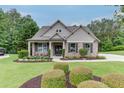 Inviting brick home featuring a landscaped front yard with mature trees and a cozy front porch with chairs at 7070 Concord Mountain Trl, Cumming, GA 30028
