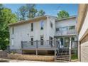 Two-story home with a grey back deck and stairs, surrounded by lush trees at 4117 Signal Sw Rdg, Lilburn, GA 30047
