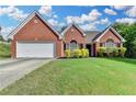 Charming, one-story brick home with well-maintained lawn, a two-car garage, and lush landscaping at 1627 Amhearst Walk Rd, Lawrenceville, GA 30043