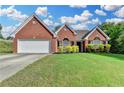 Charming, one-story brick home with well-maintained lawn, a two-car garage, and lush landscaping at 1627 Amhearst Walk Rd, Lawrenceville, GA 30043
