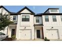 Stylish townhomes featuring white brick exteriors, black trim, and modern garage doors at 32 S Auburn Landing Pl, Auburn, GA 30011