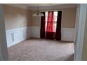 Cozy dining room with elegant wainscoting, soft carpet, and natural light from the window at 4527 Berline Dr, Lithonia, GA 30038