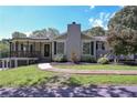 Traditional home featuring a covered porch, stone chimney, large windows, and a well-manicured front lawn at 8321 Banks Mill Rd, Douglasville, GA 30135