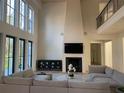 Elegant living room featuring a fireplace, TV, high ceilings, and a comfortable sectional sofa at 1303 Cobblemill Nw Way, Kennesaw, GA 30152