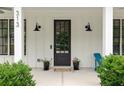 Inviting front porch with elegant black door, sconces, and potted plants at 313 Sisson Ne Ave, Atlanta, GA 30317