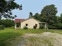 Exterior view of the single-story home with gravel driveway surrounded by trees at 361 West Ave, Dallas, GA 30157