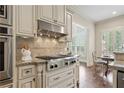 Kitchen with stainless steel stove top, range hood, tile backsplash, and granite countertops at 4530 Westgate Dr, Cumming, GA 30040