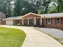 Traditional brick home boasts a long driveway and inviting curb appeal with a manicured lawn at 4807 Greenway Rd, Norcross, GA 30071