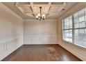 Elegant dining room with a coffered ceiling, wainscoting, hardwood floors, and a large window at 1205 Apple Blossom Dr, Cumming, GA 30041