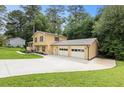 A two-story home featuring a two-car garage and long driveway, surrounded by lush greenery and lawn at 423 Mephisto Cir, Lawrenceville, GA 30046