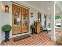 Inviting front porch with double wooden front doors, brick flooring, welcome mat, and stylish seating area at 6655 Manchester Pl, Cumming, GA 30040
